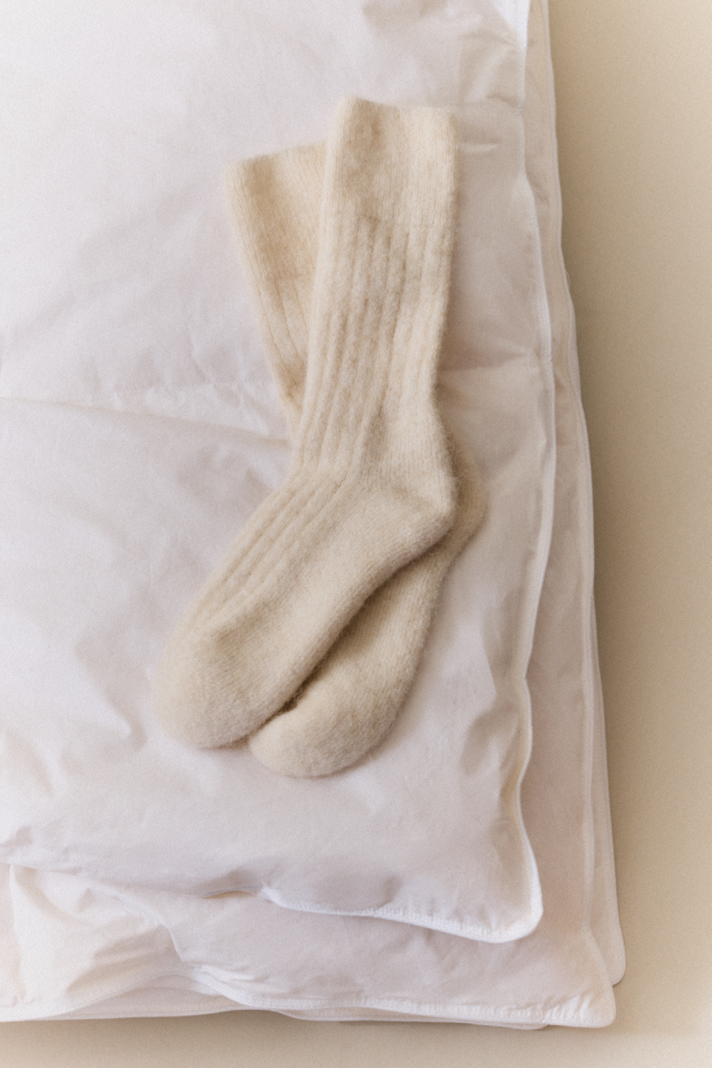 Cream alpaca bed socks on a duvet