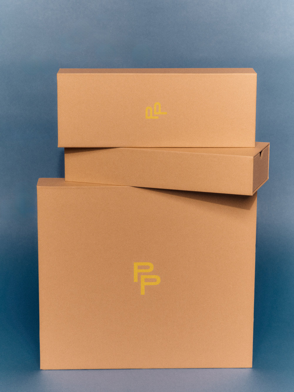 Three Pairs gift boxes stacked on top of each other with yellow logos on a blue background