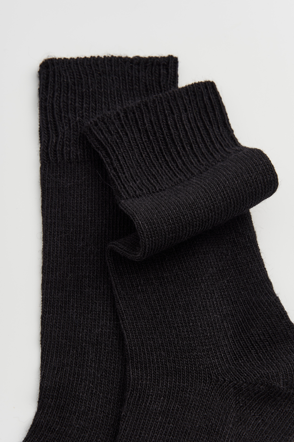 Pair of black calf-length alpaca socks on a light grey background