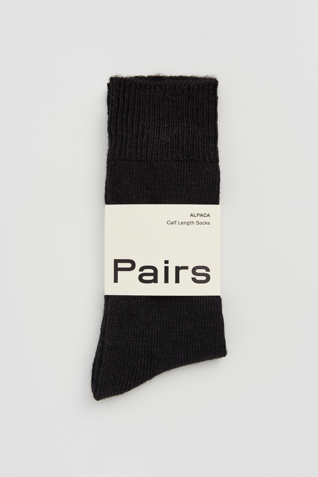 Black calf-length alpaca sock with a 'Pairs' packaging band on a light grey background