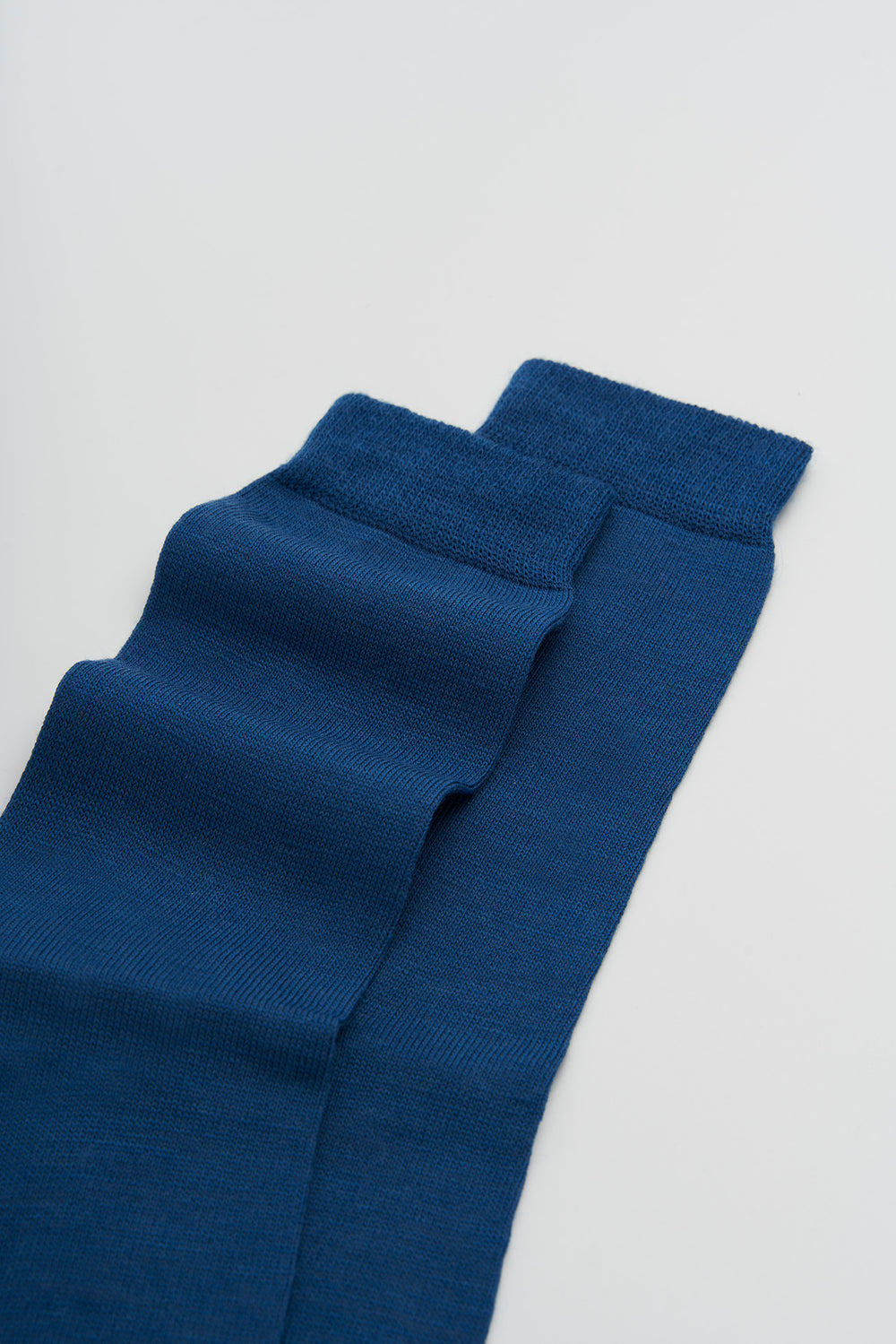 Pair of blue merino socks on a light grey background