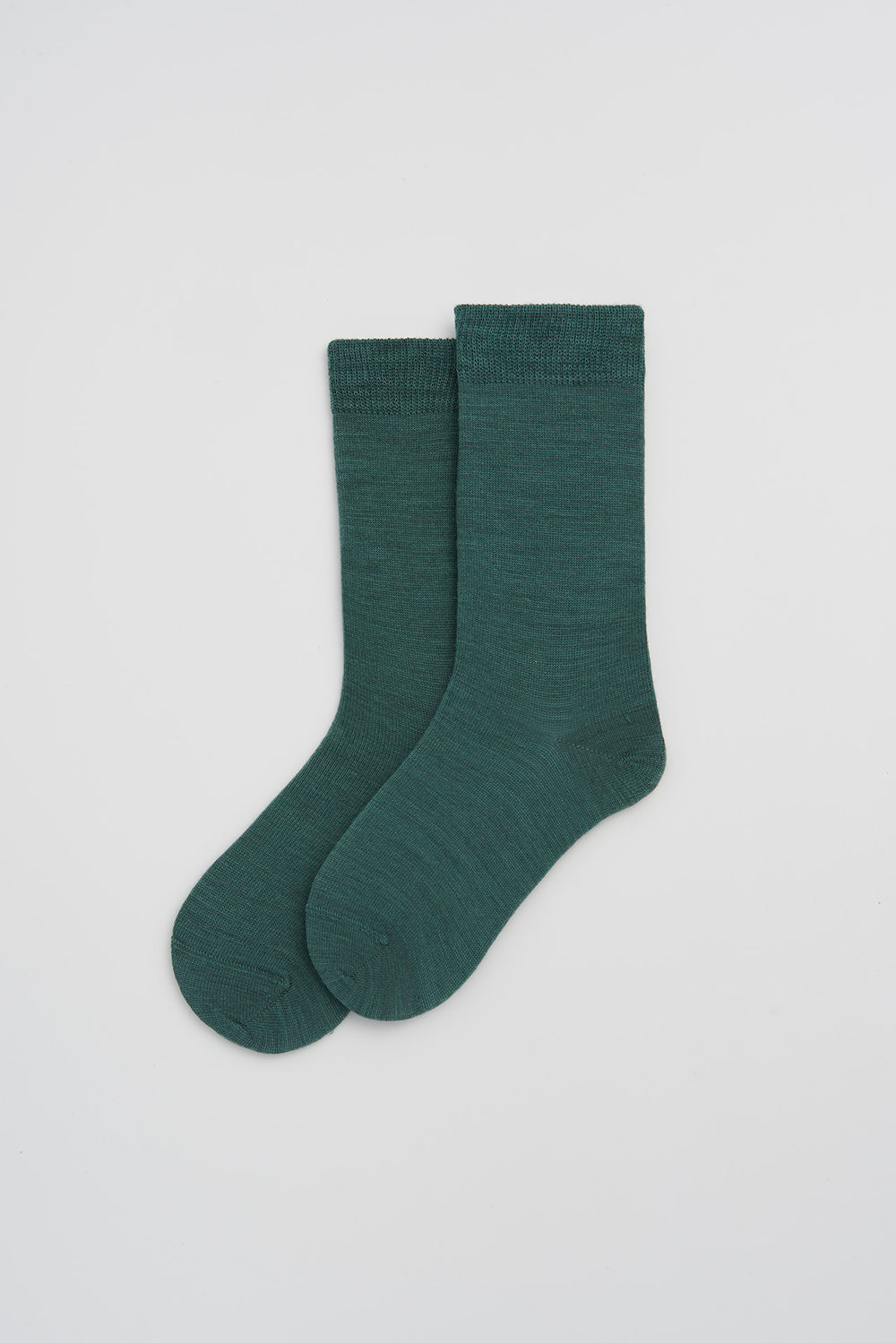Pair of pine green merino socks on a light grey background