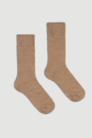 Pair of beige calf length alpaca socks on a light grey background