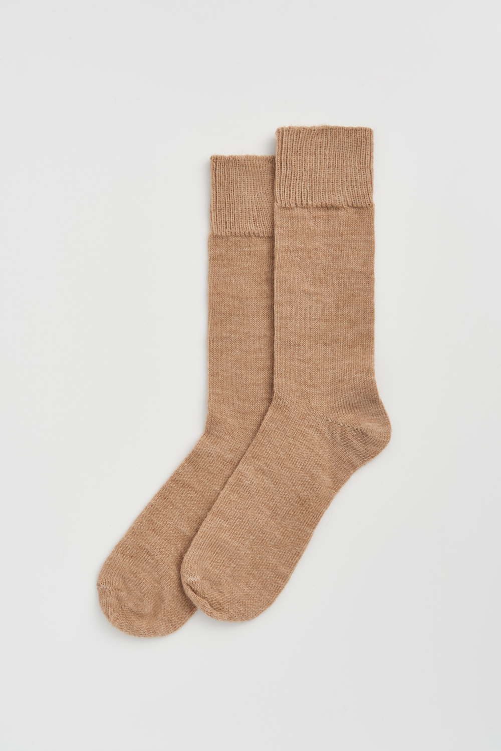 Pair of beige calf-length alpaca socks  on a light grey background