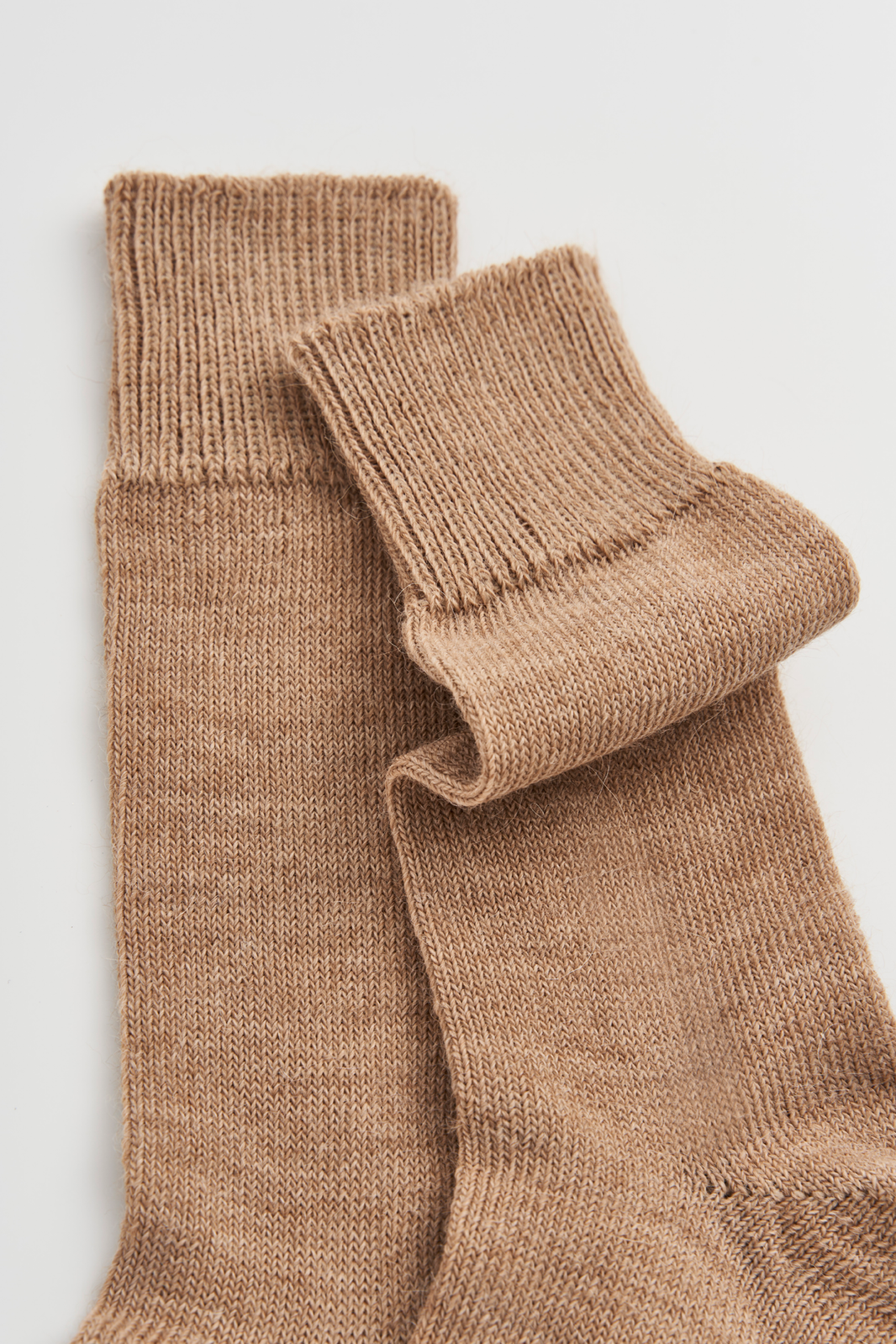Pair of beige calf-length alpaca socks  on a light grey background