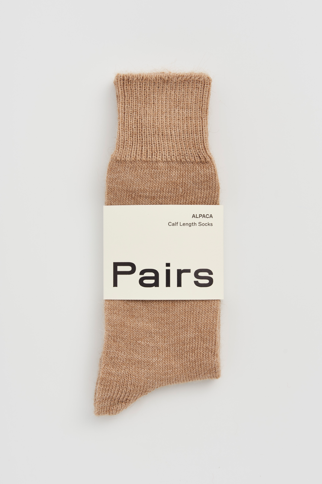 Beige calf-length alpaca sock with a 'Pairs' packaging band on a light grey background