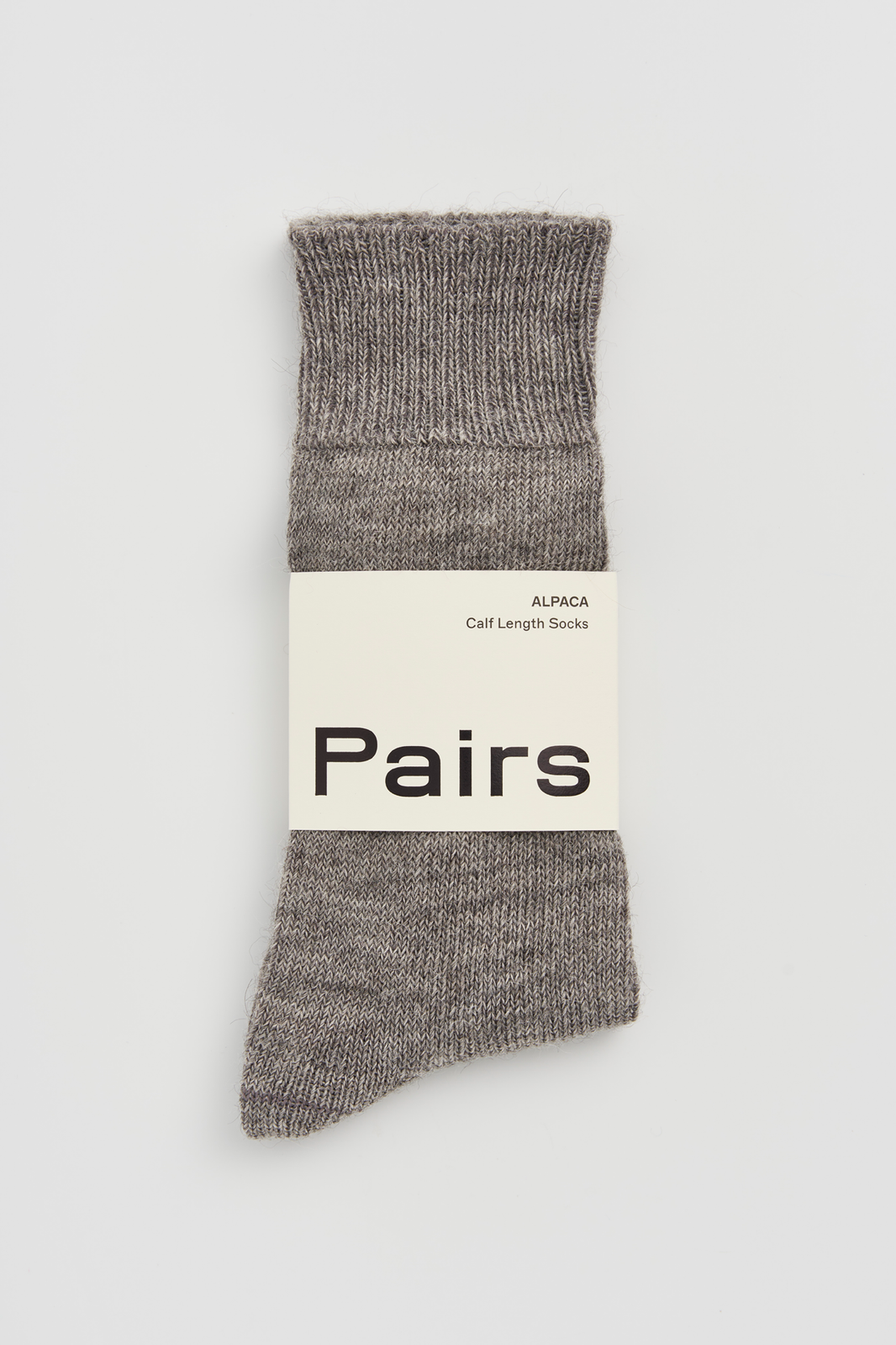 Pair of grey calf-length alpaca socks with a 'Pairs' packaging band on a light grey background