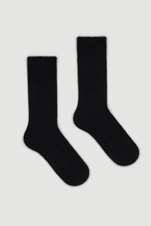 Pair of black calf length alpaca socks on a light gray background
