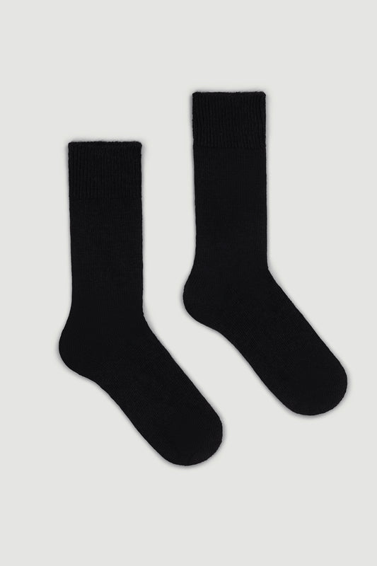 Pair of black calf length alpaca socks on a light gray background