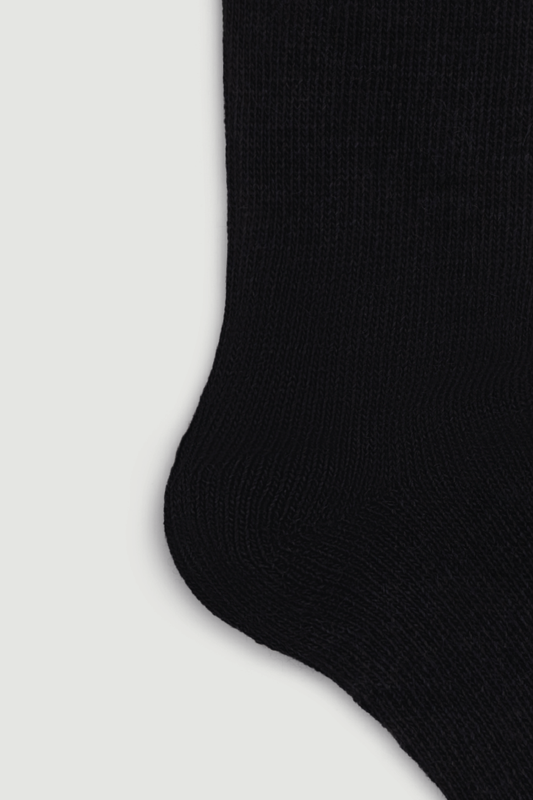 Close up of the heel of a black calf length alpaca sock on a white background