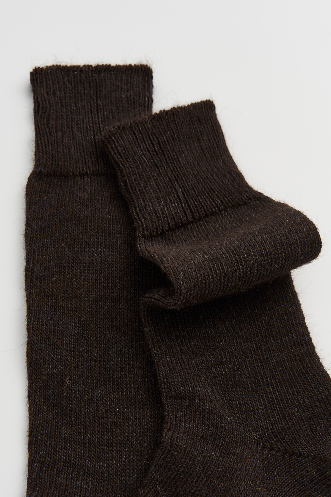 Pair of dark brown calf-length alpaca socks on a light grey background