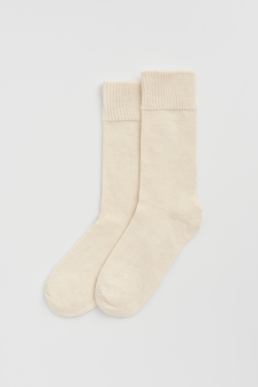 Pair of cream calf-length alpaca socks on a light grey background
