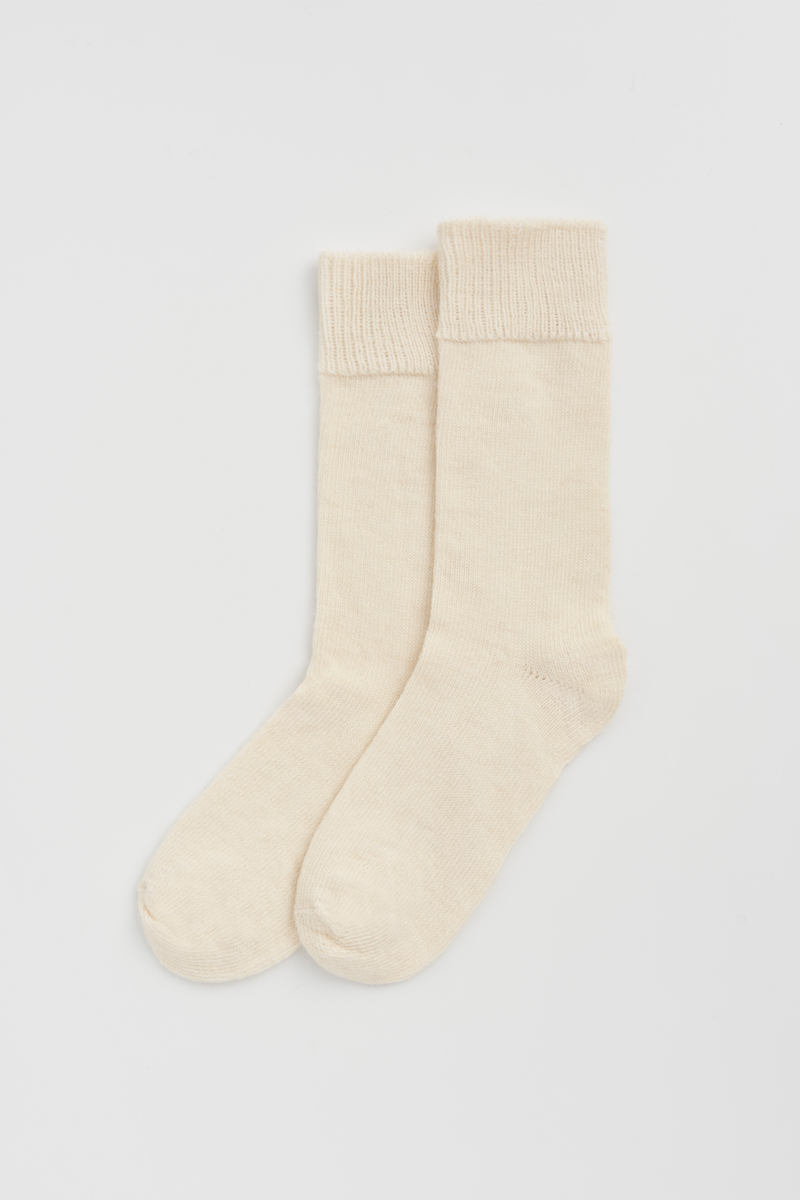 Pair of cream calf-length alpaca socks on a light grey background