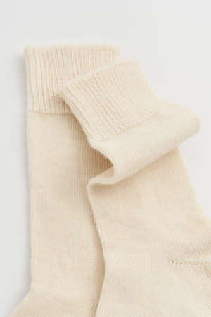 Pair of cream calf-length alpaca socks on a light grey background