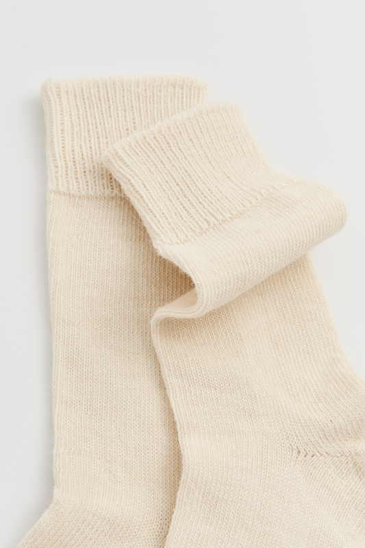 Pair of cream calf-length alpaca socks on a light grey background