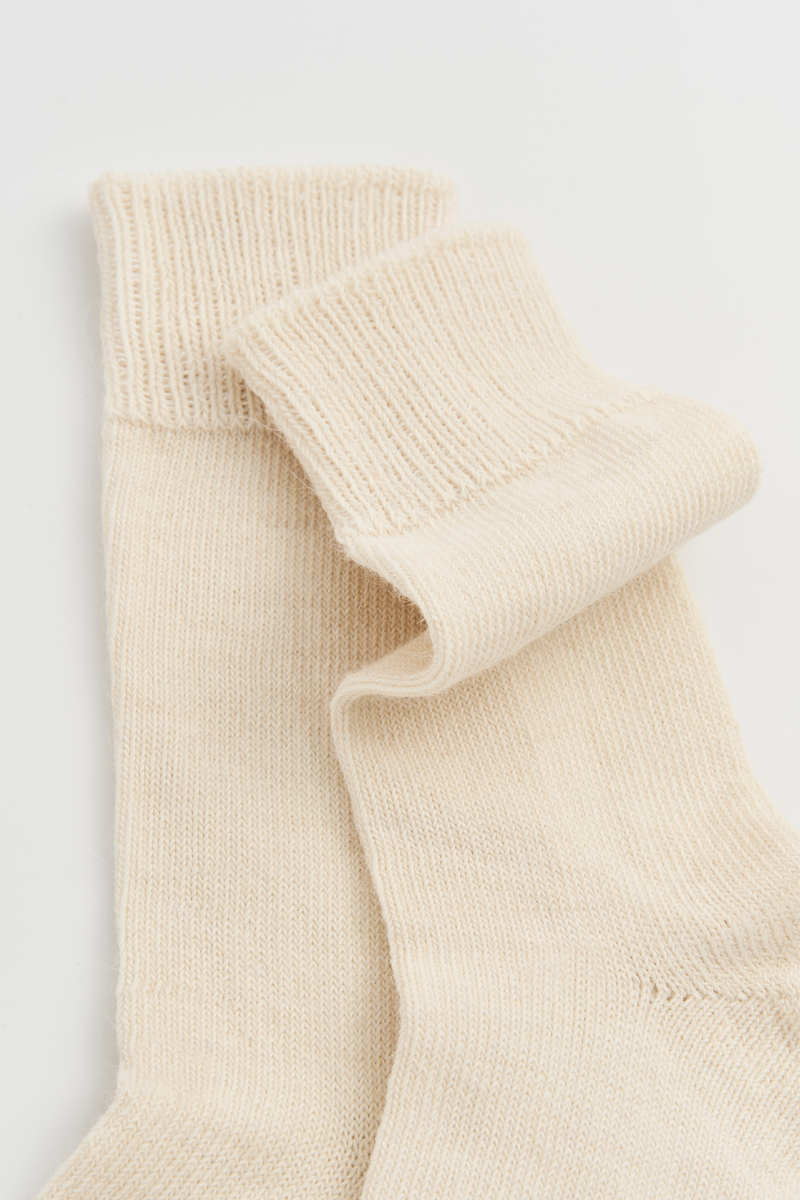 Pair of cream calf-length alpaca socks on a light grey background