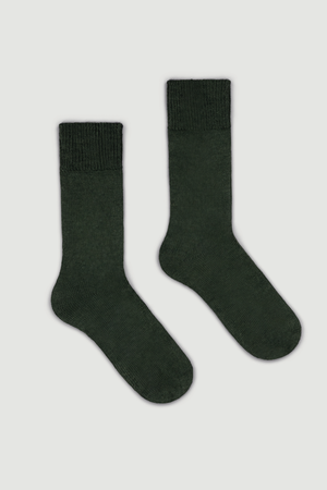 Pair of dark green calf length alpaca socks on a light grey background