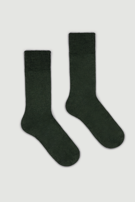 Pair of dark green calf length alpaca socks on a light grey background