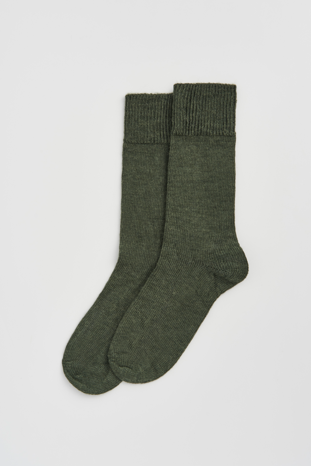 Pair of green calf-length alpaca socks on a light grey background