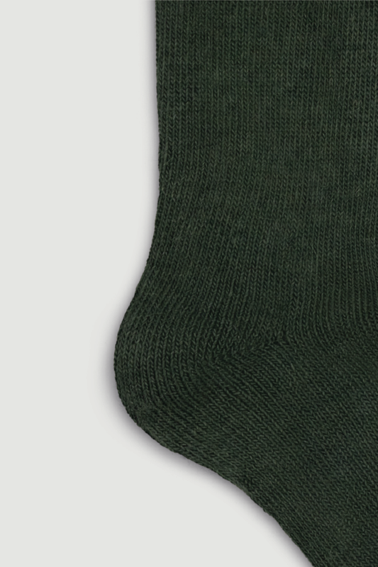 Close-up of the heel of a green calf length alpaca sock on a white background