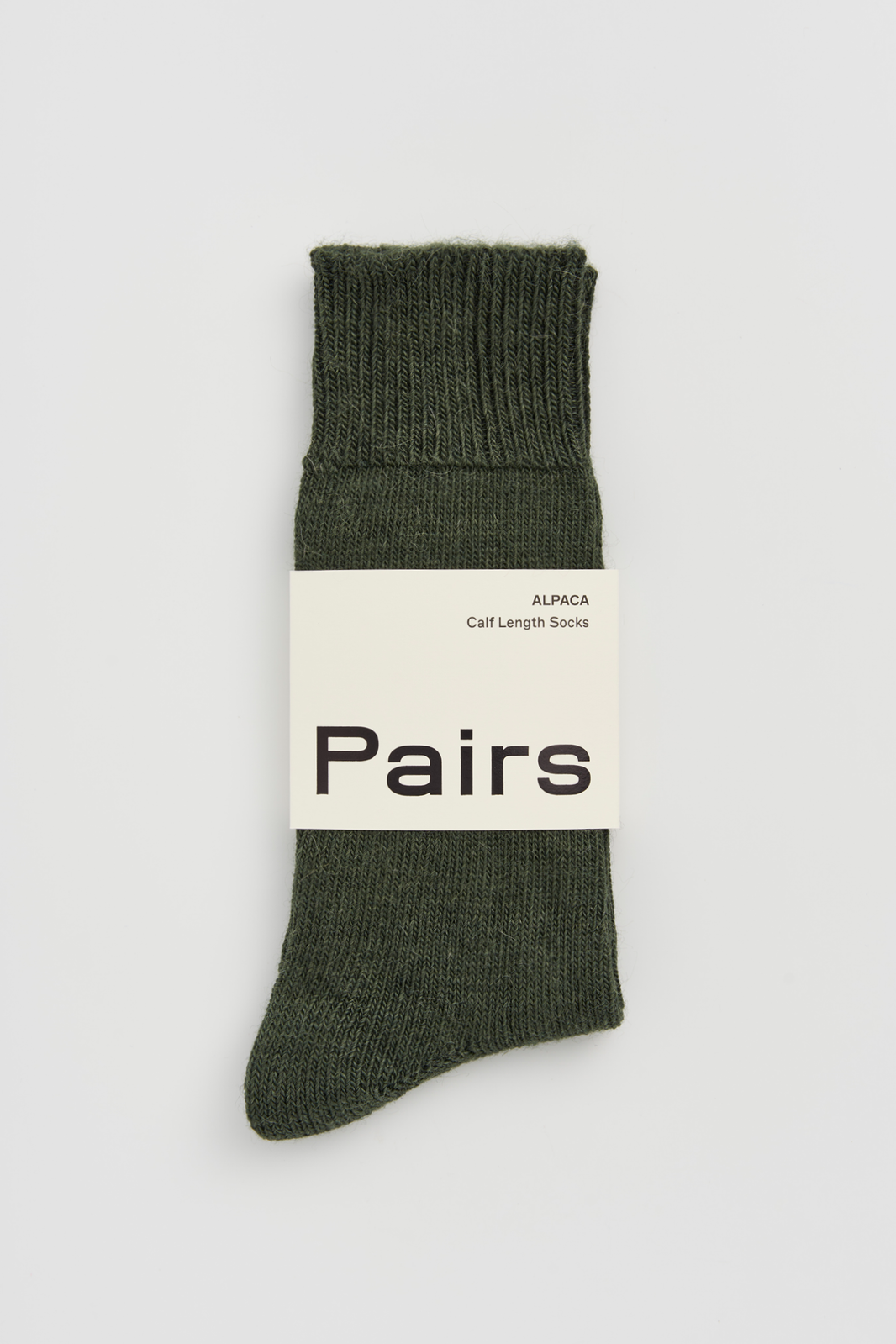 Green calf-length alpaca sock with a 'Pairs' packaging band on a light grey background