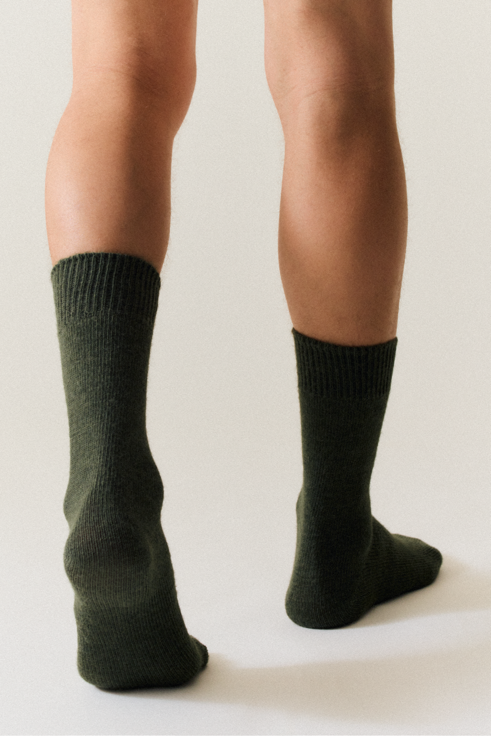 Person wearing dark green calf length alpaca socks