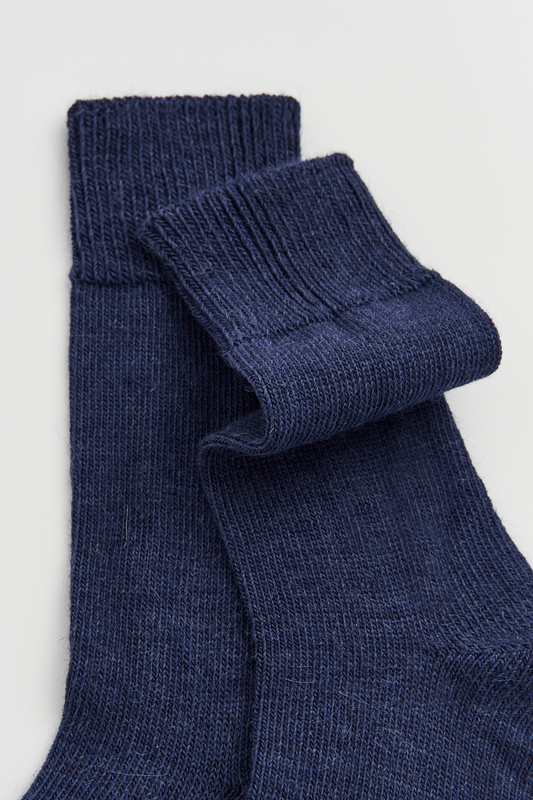 Close-up of a pair of blue calf-length alpaca socks on a light grey background