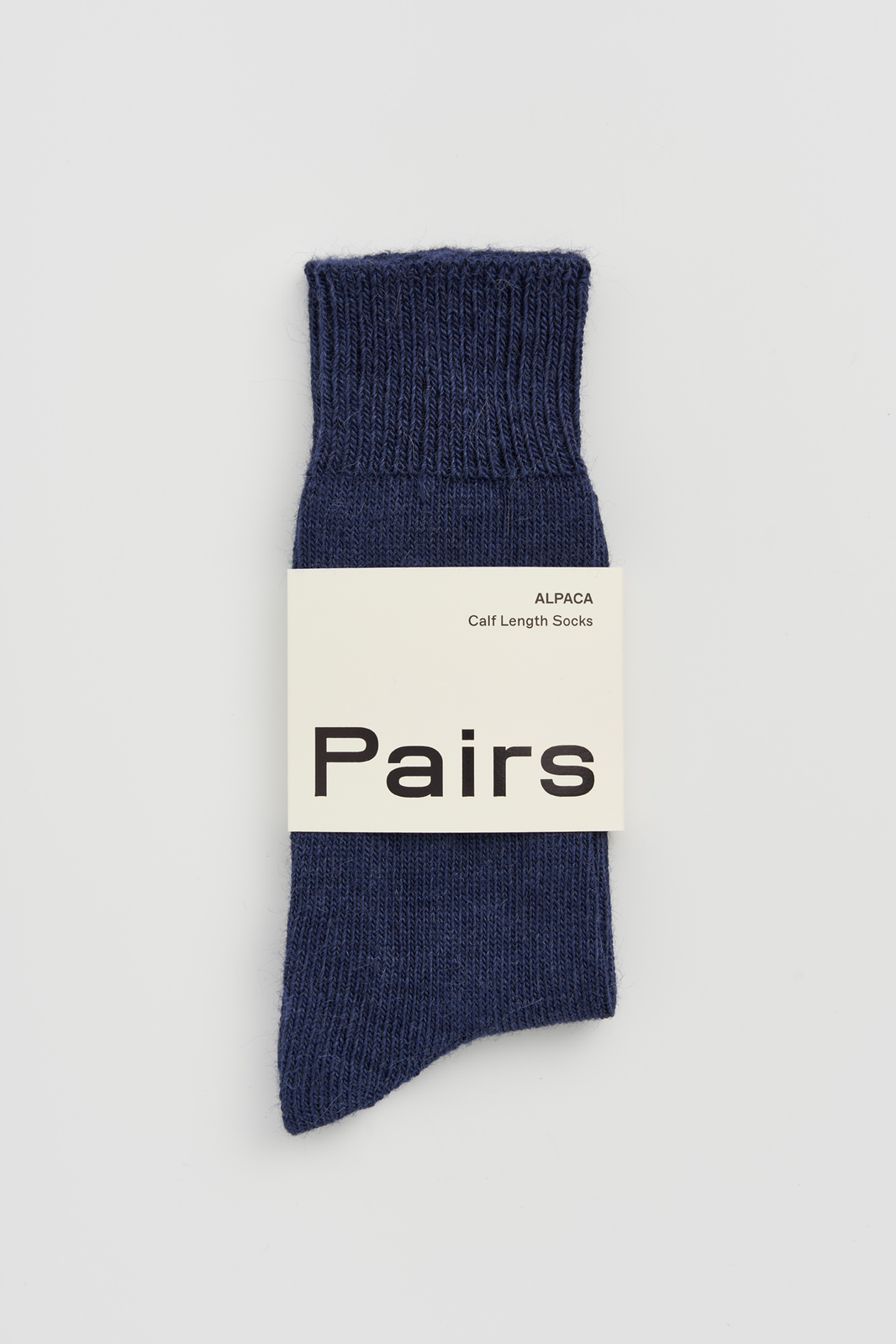 Navy calf-length alpaca sock with a 'Pairs' packaging band on a light grey background