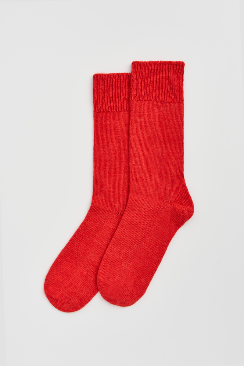 Pair of red calf-length alpaca socks on a light grey background