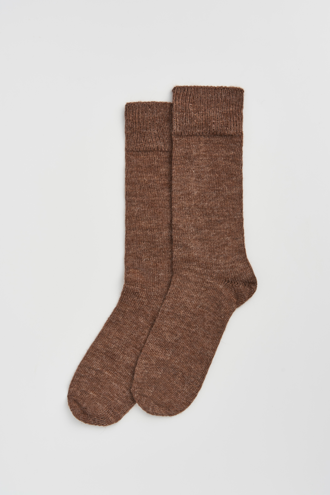Pair of mid-brown calf-length alpaca socks on a light grey background