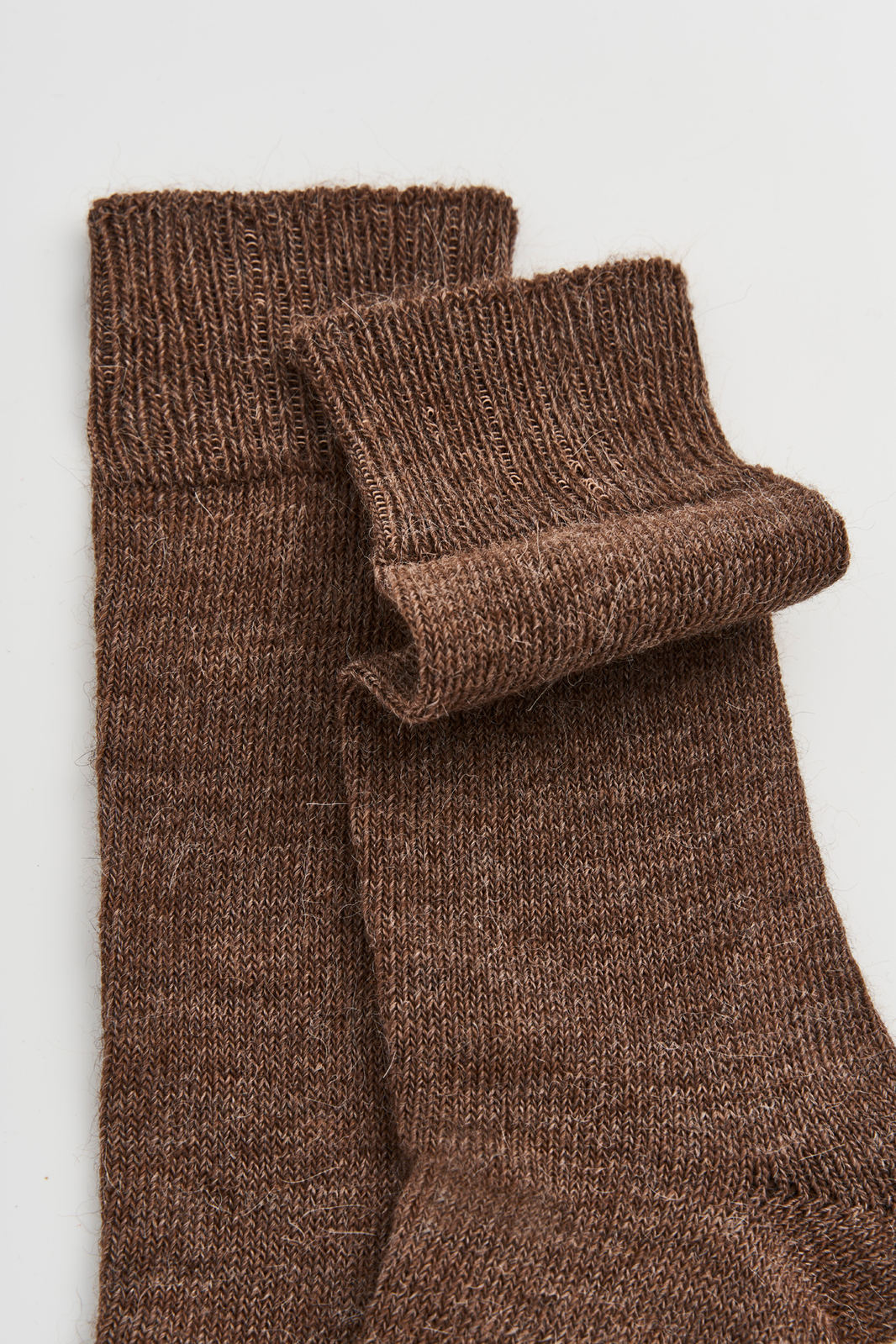 Pair of mid-brown calf-length alpaca socks on a light grey background
