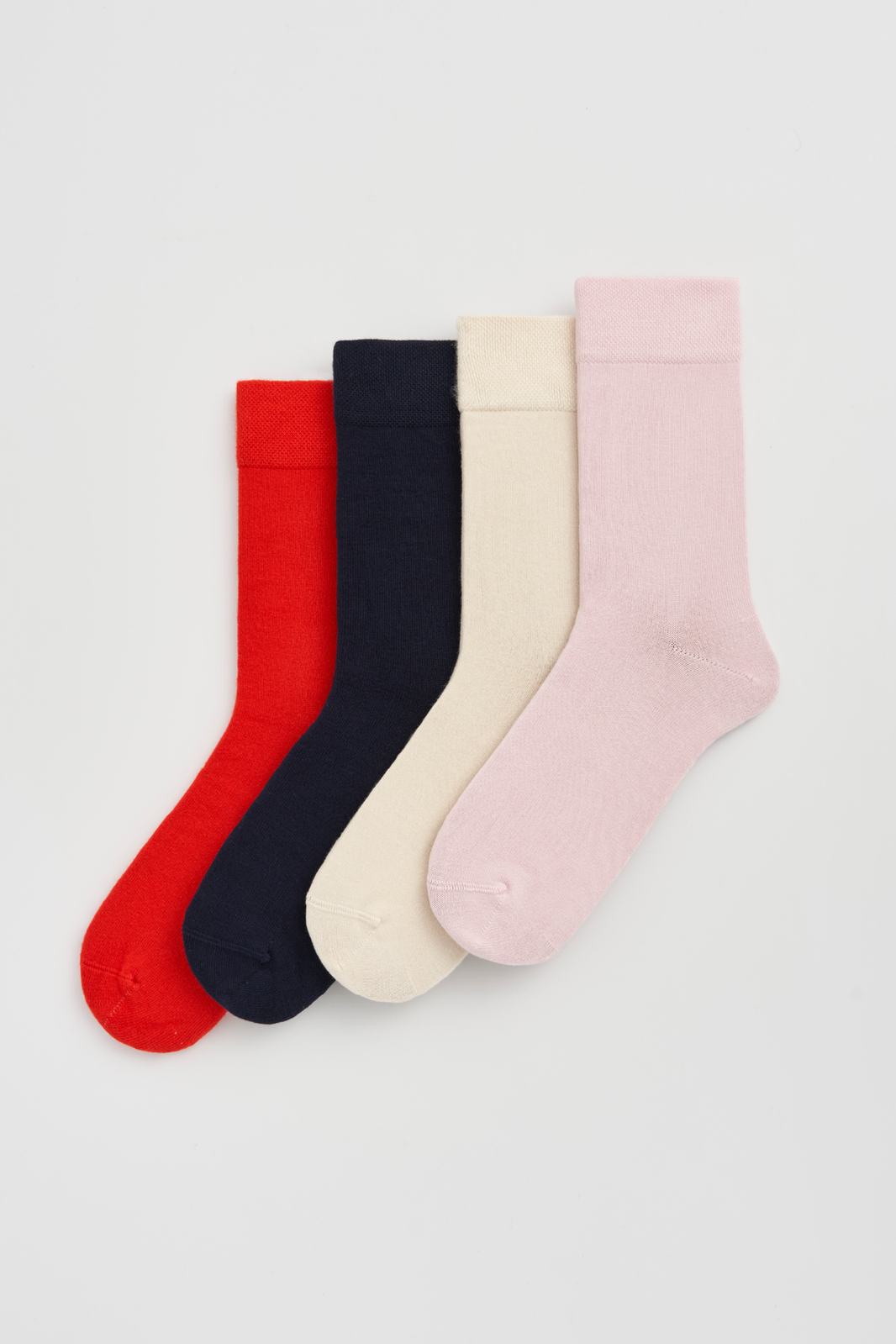 Four pairs of colourful calf-length bamboo socks (red, navy blue, cream and pink) on a light grey background