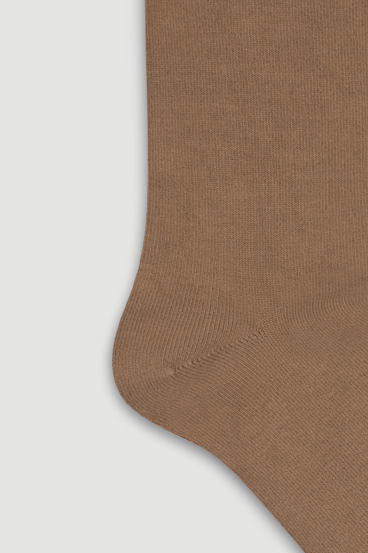 Close-up of the heel of a light brown bamboo calf length sock on a light grey background