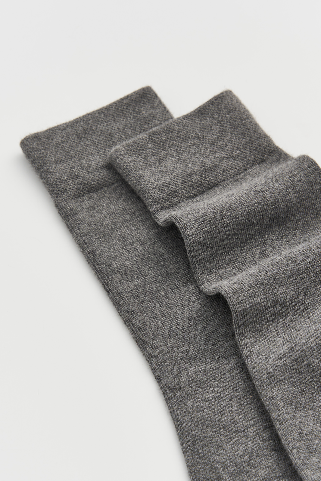 Close-up of the top of a pair of grey calf-length bamboo socks on a light grey background