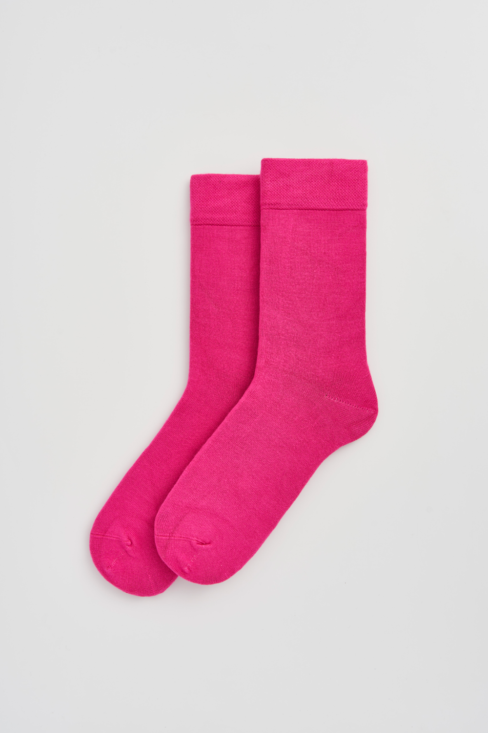 Pair of bright pink calf-length bamboo socks on a light grey background