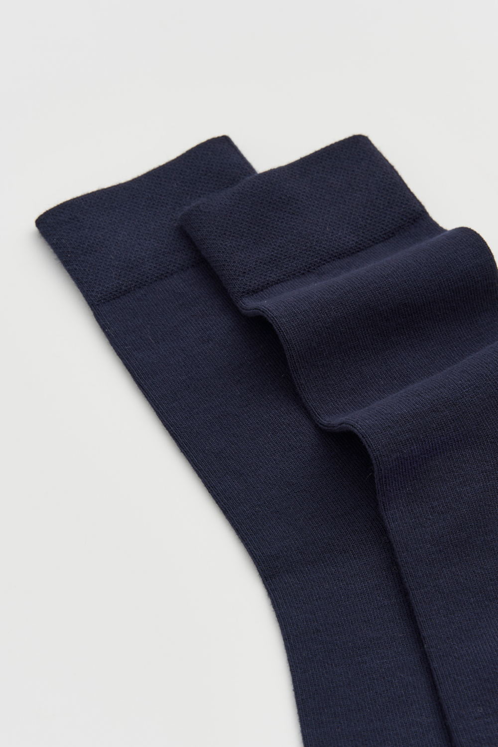 Pair of navy calf-length bamboo socks on a light grey background