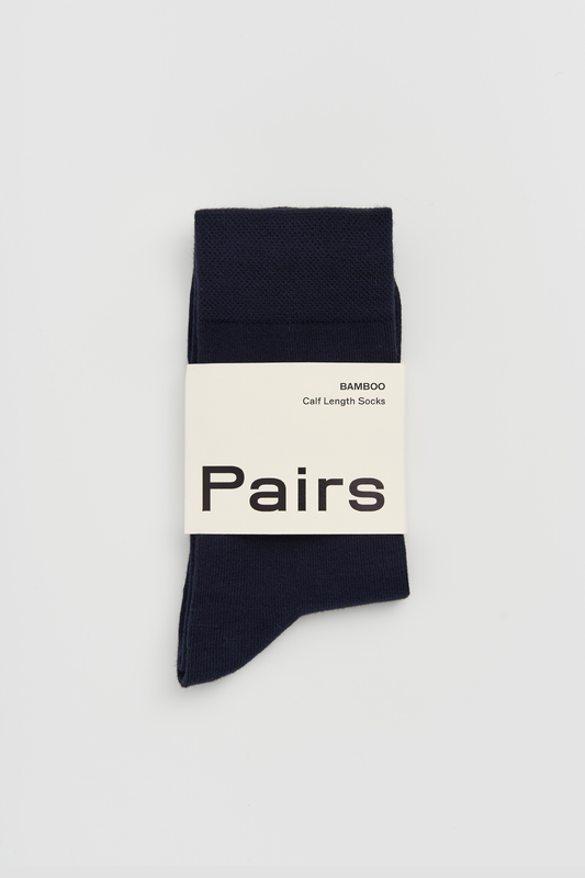 Pair of navy calf-length bamboo socks with a 'Pairs' packaging band on a light grey background