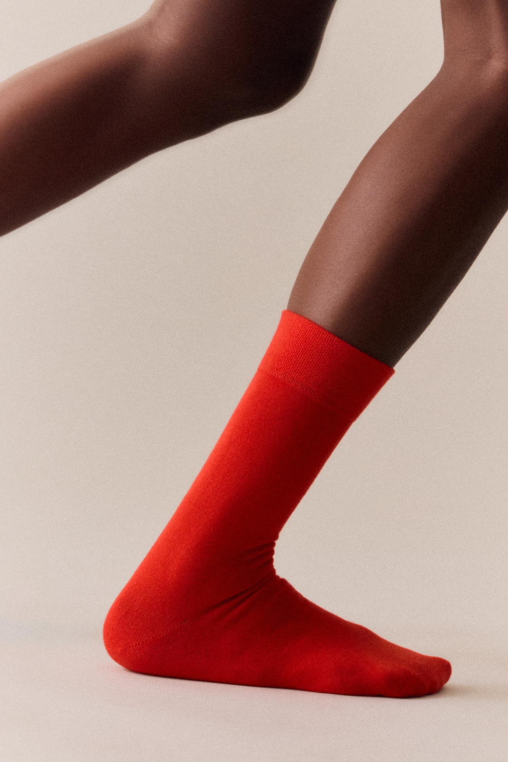 Red calf-length bamboo socks worn by a person on a beige background