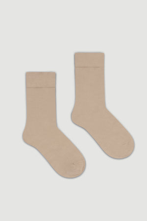 Pair of beige bamboo calf length socks on a light grey background