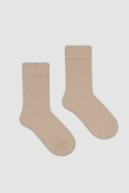 Pair of beige bamboo calf length socks on a light grey background