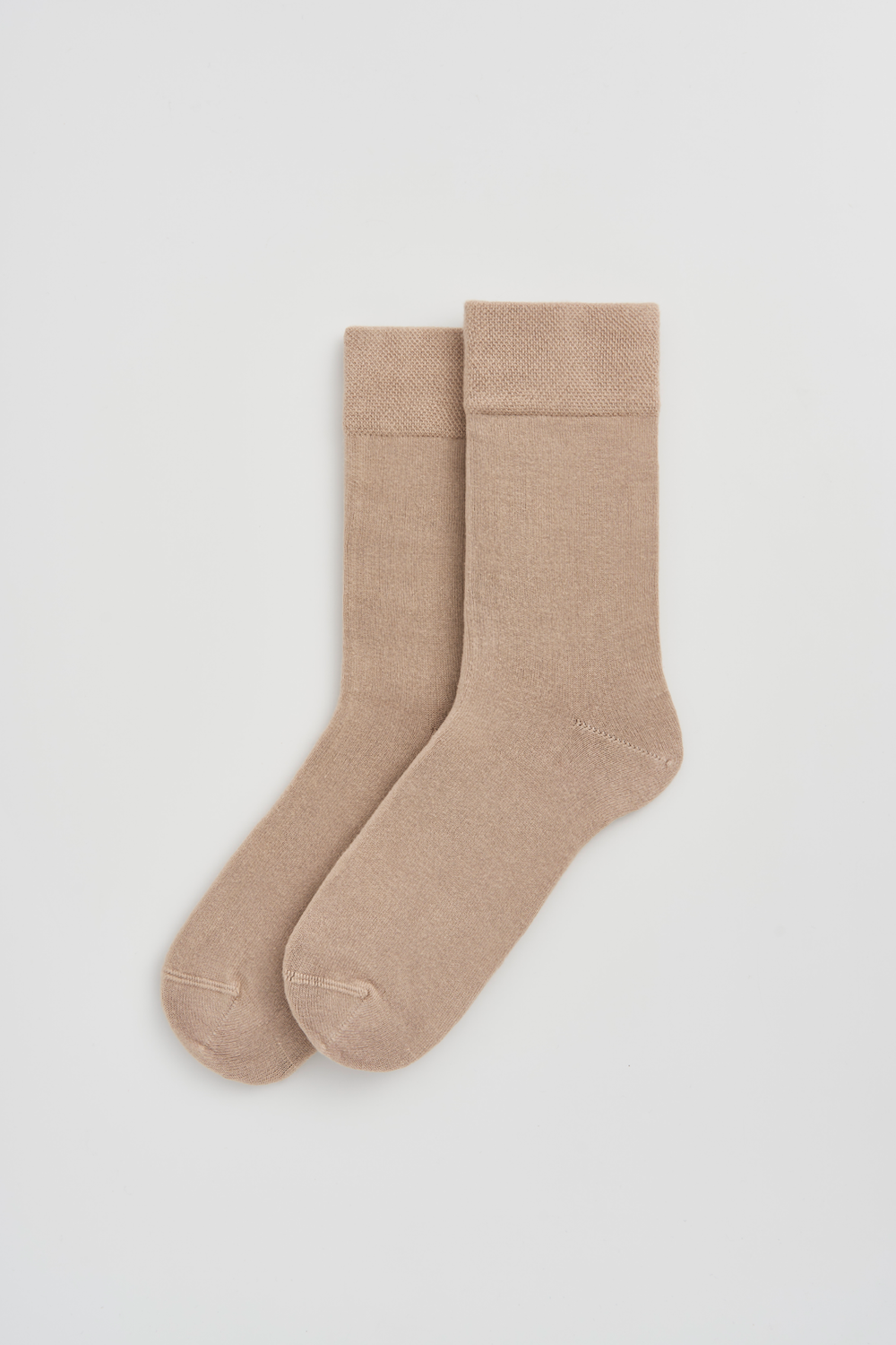 Pair of light beige calf-length bamboo socks on a light grey background