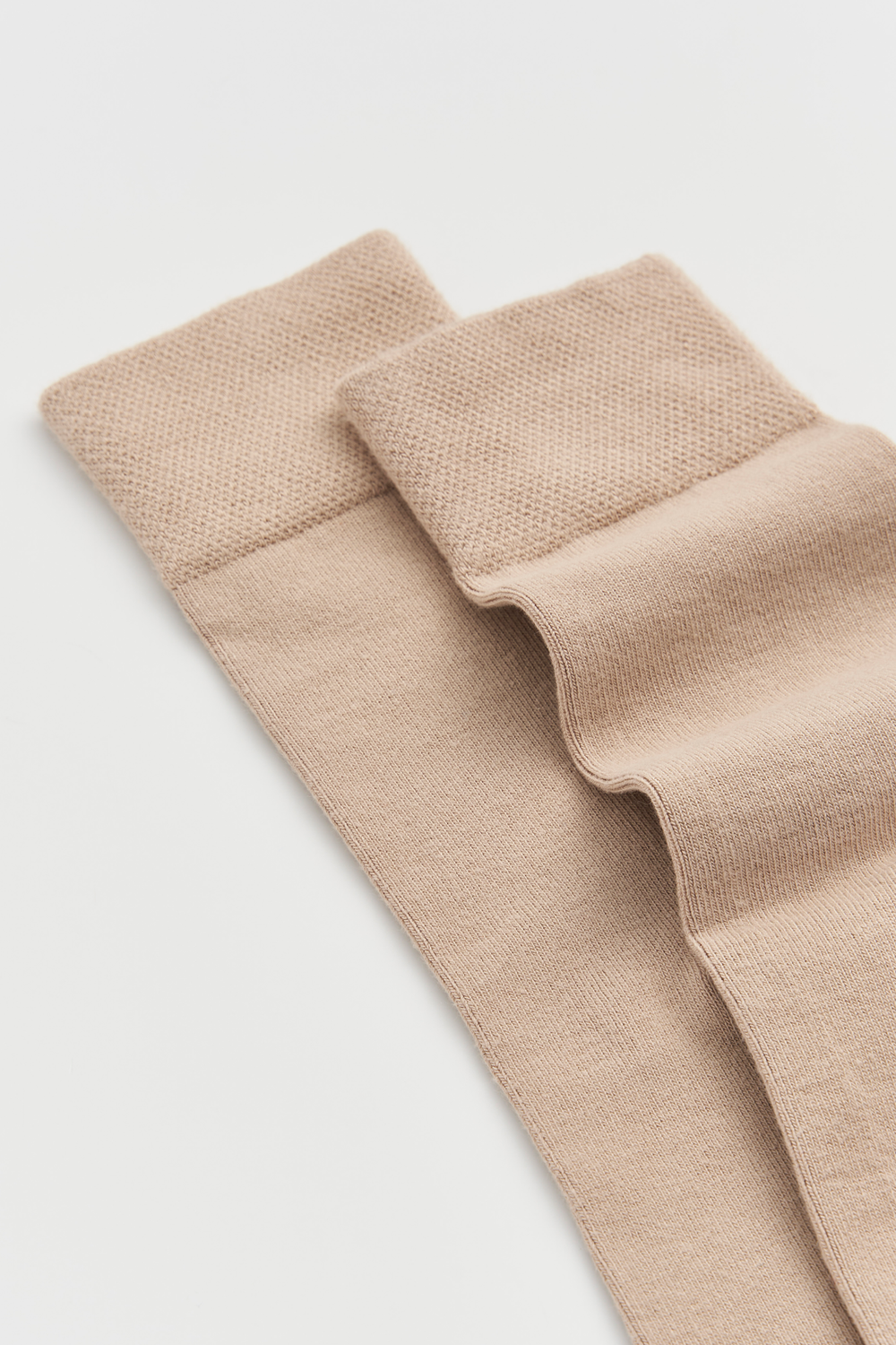 Pair of light beige calf-length bamboo socks on a light grey background