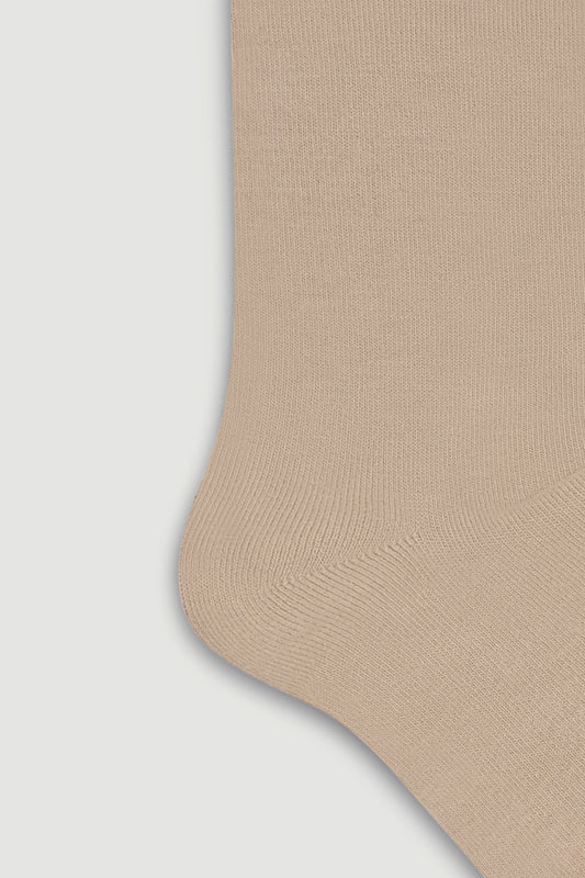 Close-up of the heel of a beige bamboo calf length sock on a light grey background
