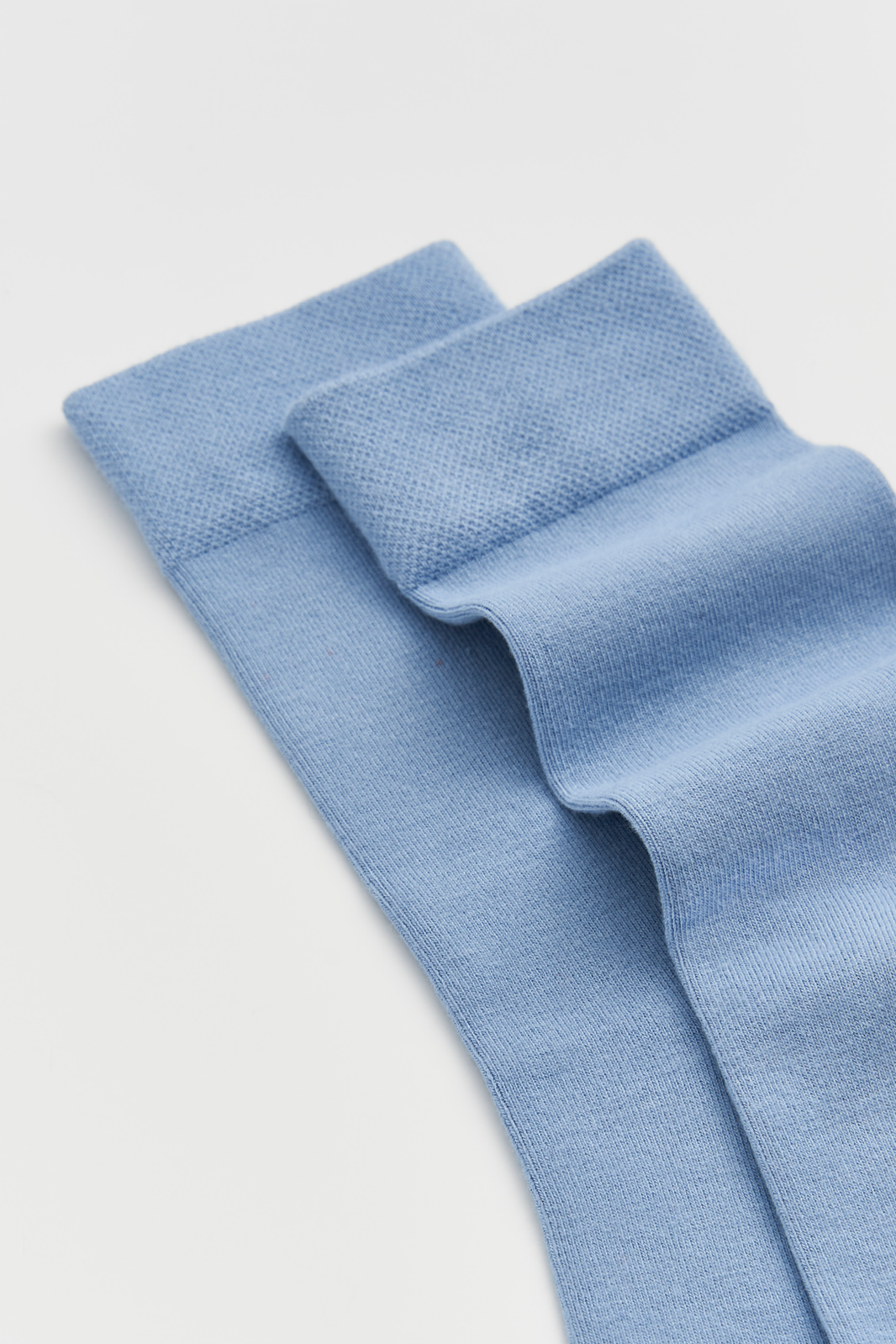 Blue calf-length bamboo socks on a light grey background