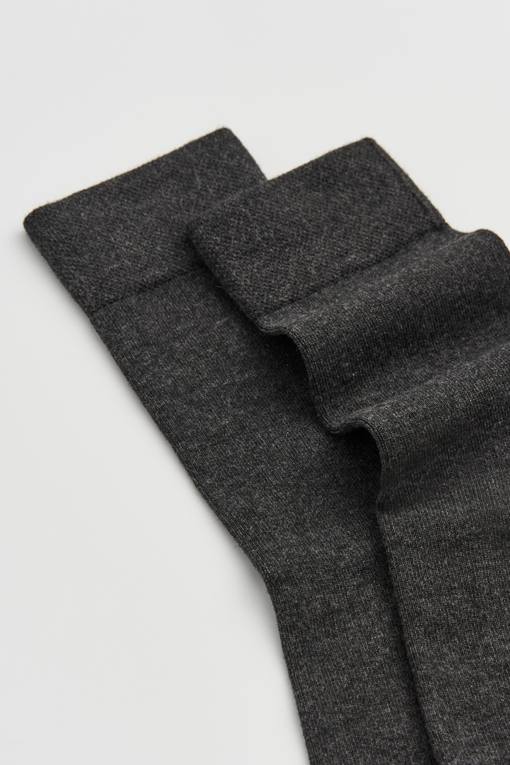 Close-up of a pair of dark grey calf-length bamboo socks  on a light grey background