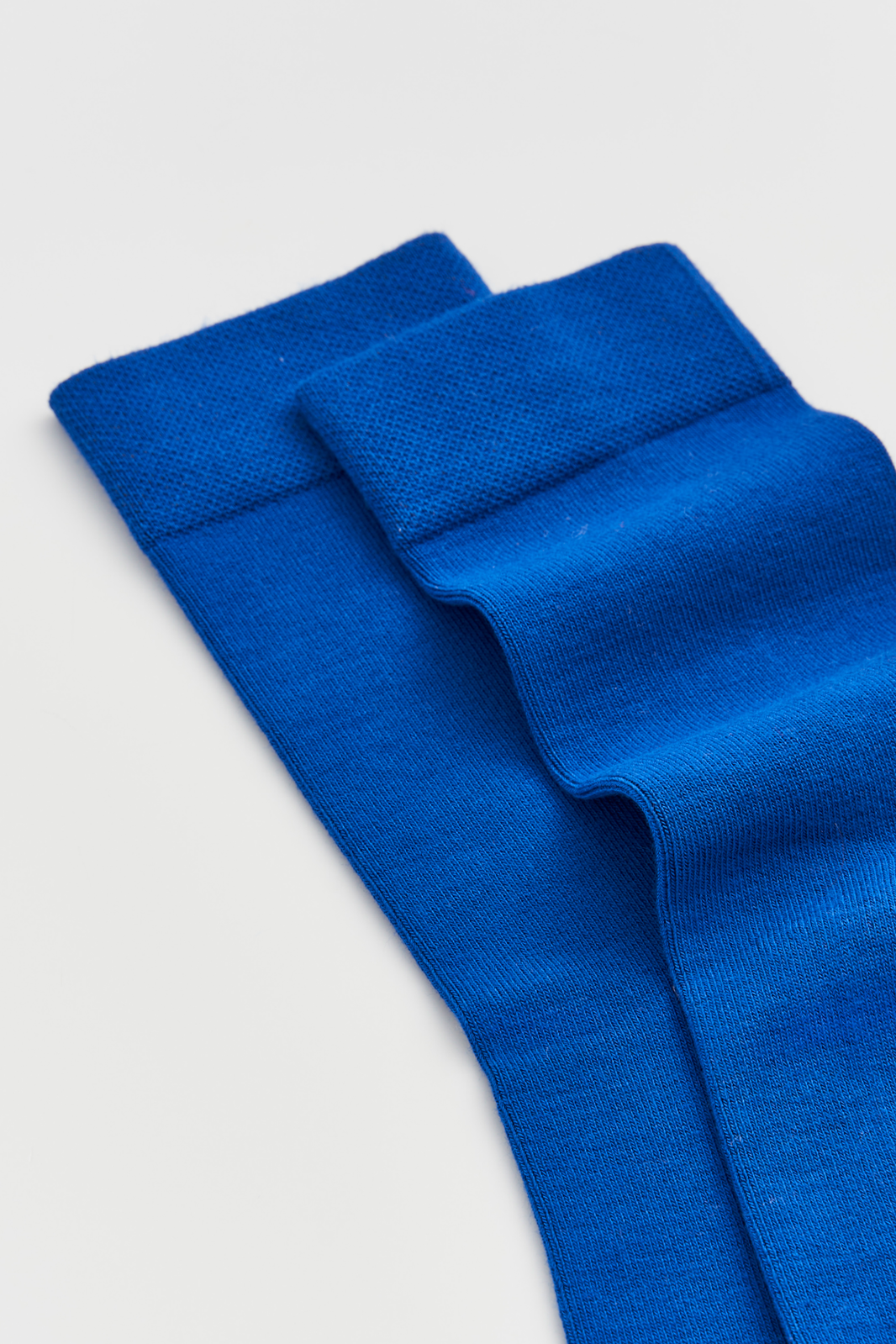 Close-up of a pair of bright blue calf-length bamboo socks on a light grey background