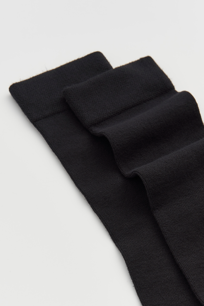 Black calf-length bamboo socks on a light grey background
