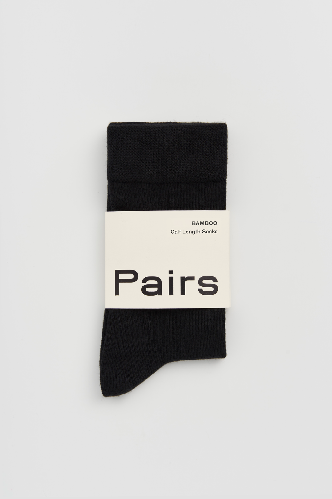 Black calf-length bamboo socks with a 'Pairs' packaging band on a light grey background
