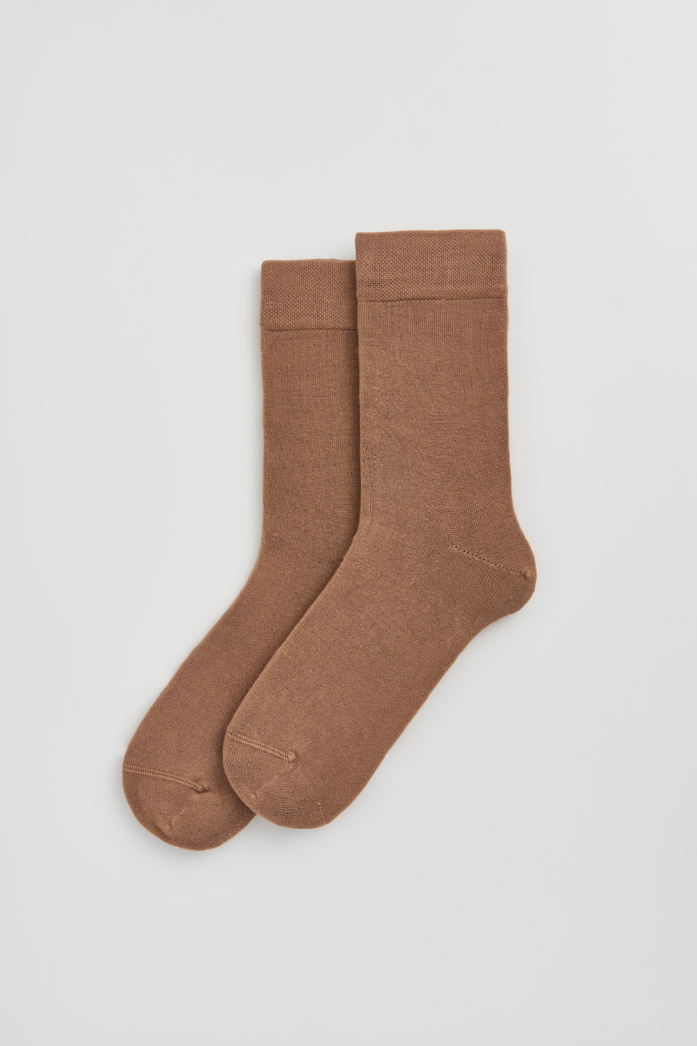 Pair of beige calf-length bamboo socks on a light grey background