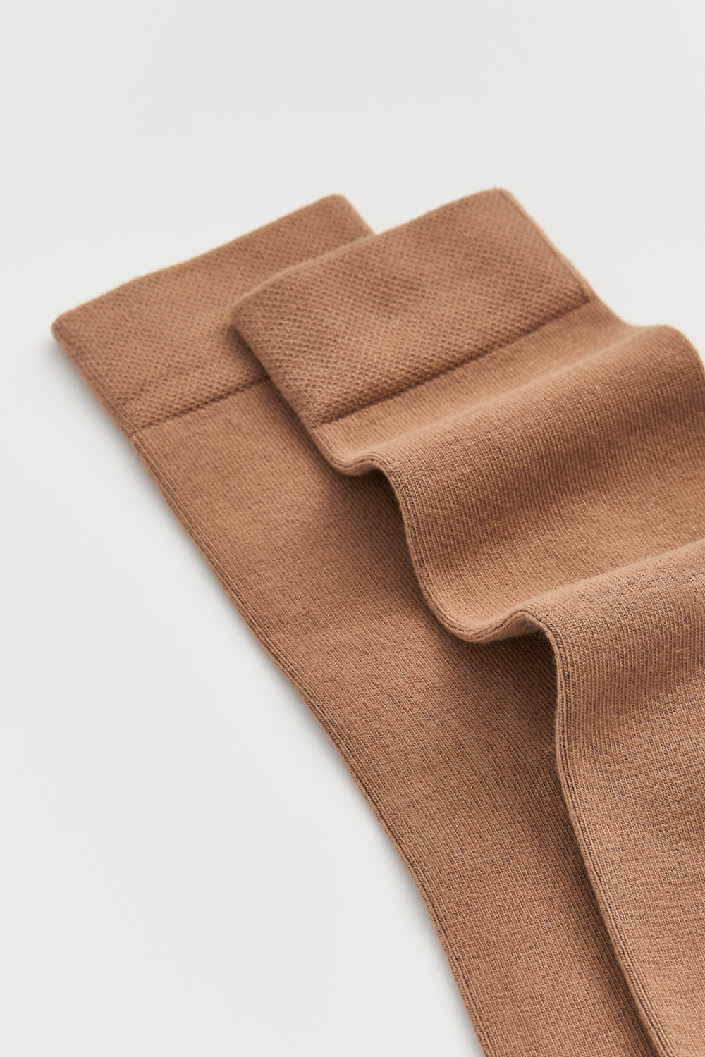 Beige calf-length bamboo socks on a light grey background